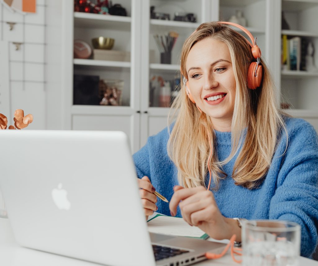 Vrouw zit met koptelefoon achter laptop thuis te werken