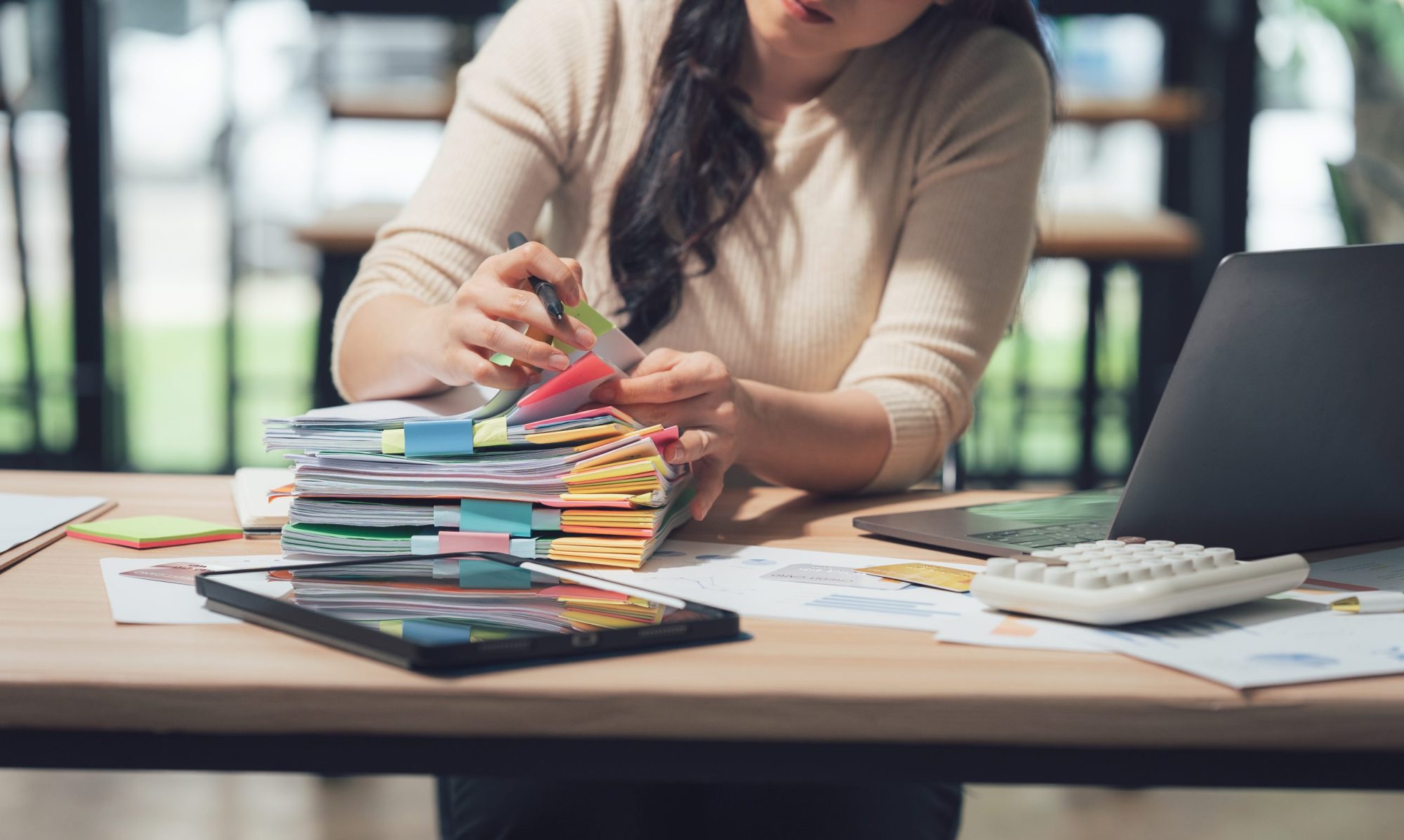 Vrouw zit achter bureau met stapel documenten