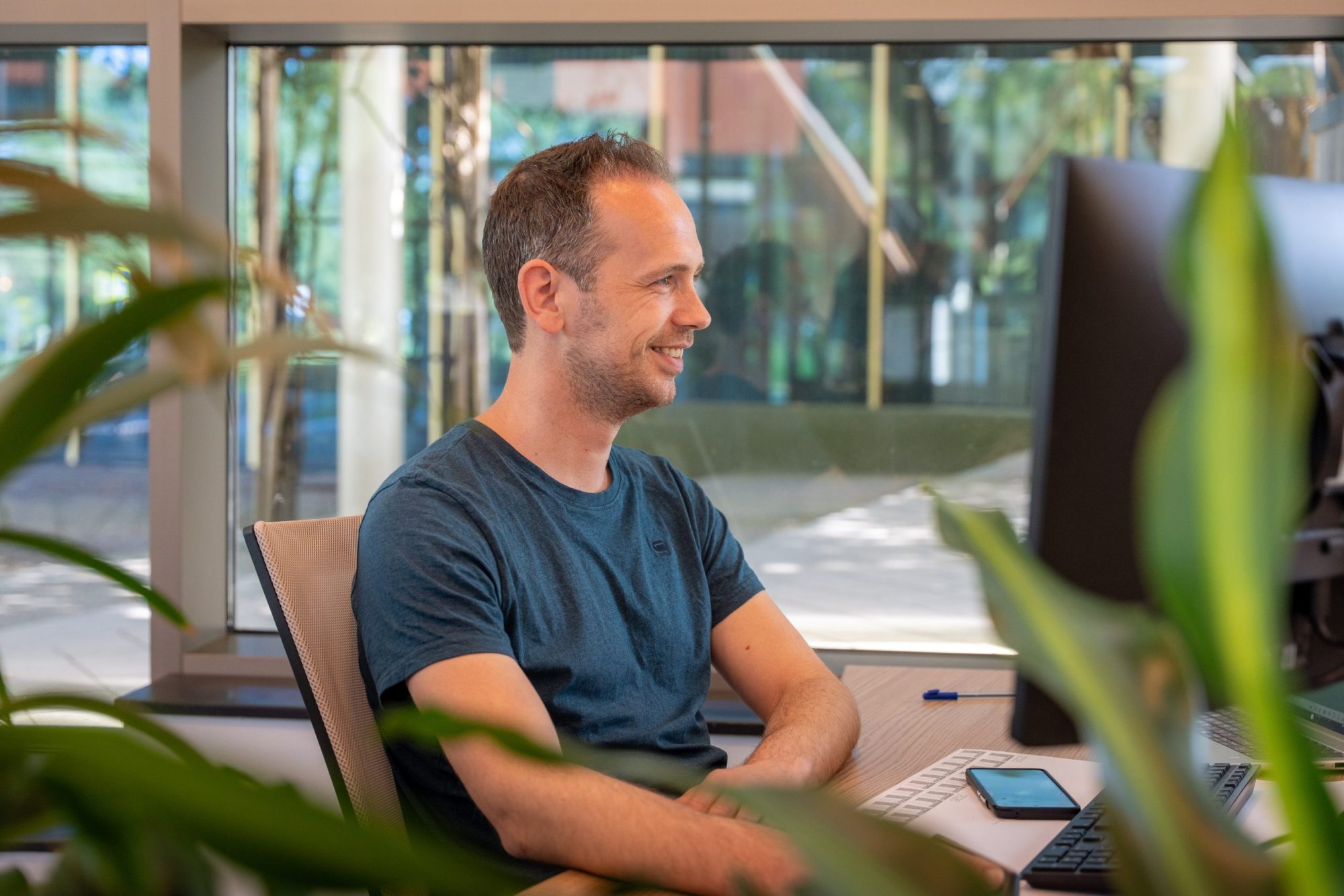 Mannelijke collega van Antenna die achter zijn bureau naar zijn beeldscherm kijkt.