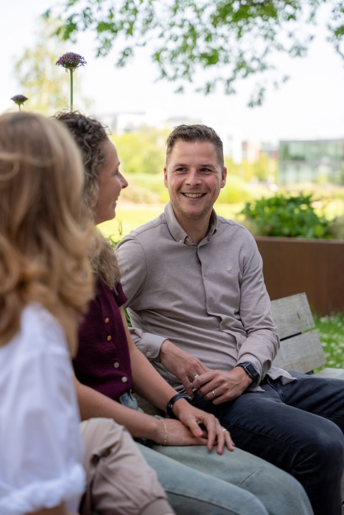Groepje collega's van Antenna op een bankje buiten, een mannelijke collega lacht naar een van de anderen