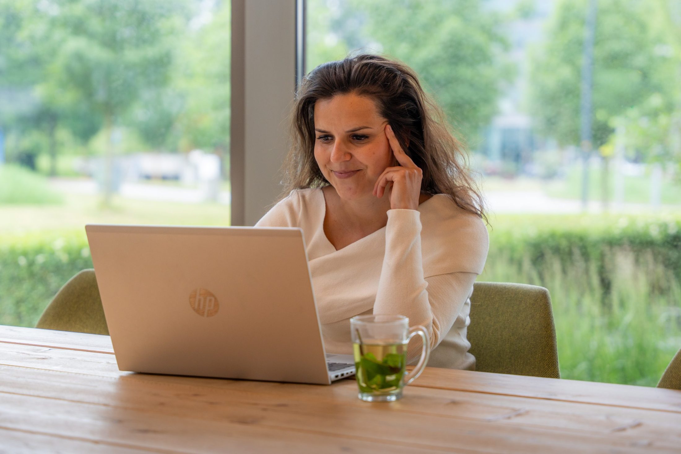Antenna collega zit aan tafel achter laptop en kijkt naar scherm