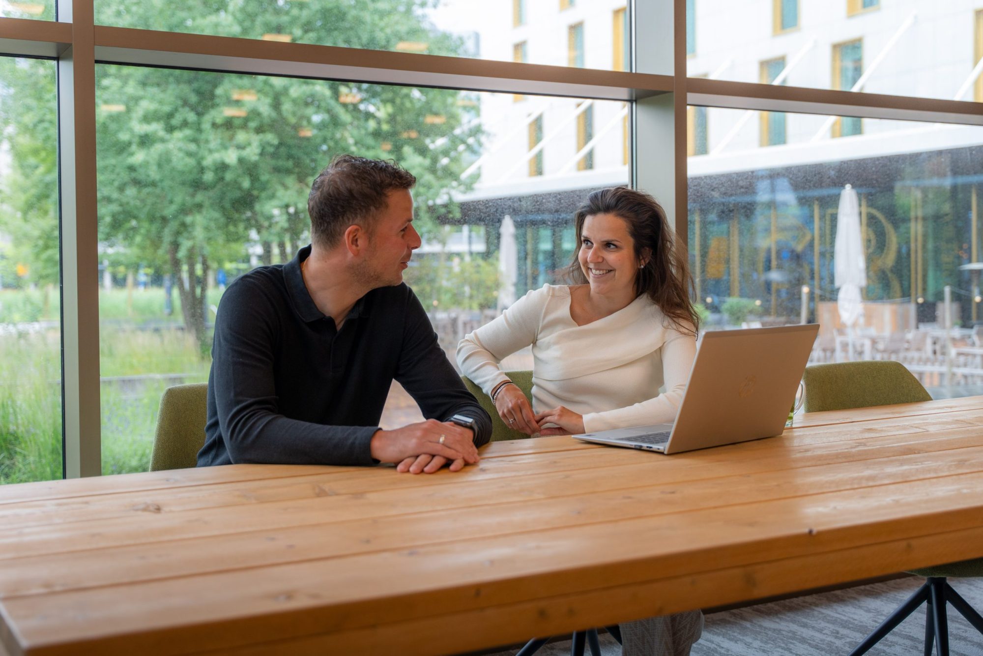 Twee collega's van Antenna, een man en een vrouw, in overleg aan een tafel met een laptop.