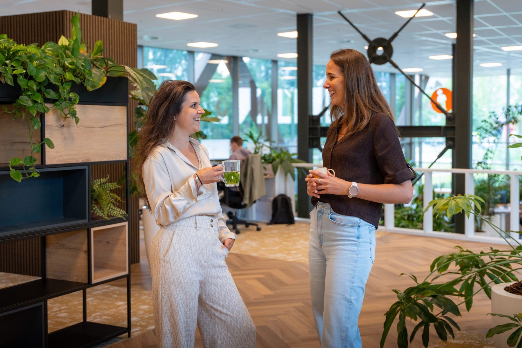 2 collega's van Antenna die op de werkvloer van het kantoor staan te praten