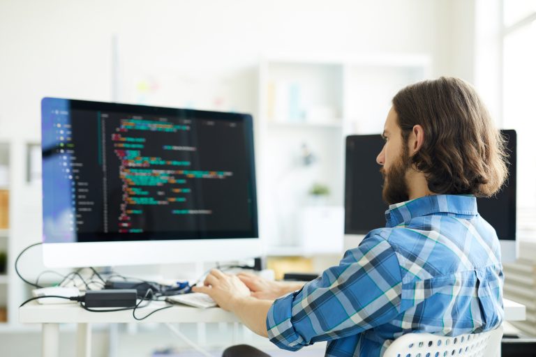 Man zit achter computer te coderen