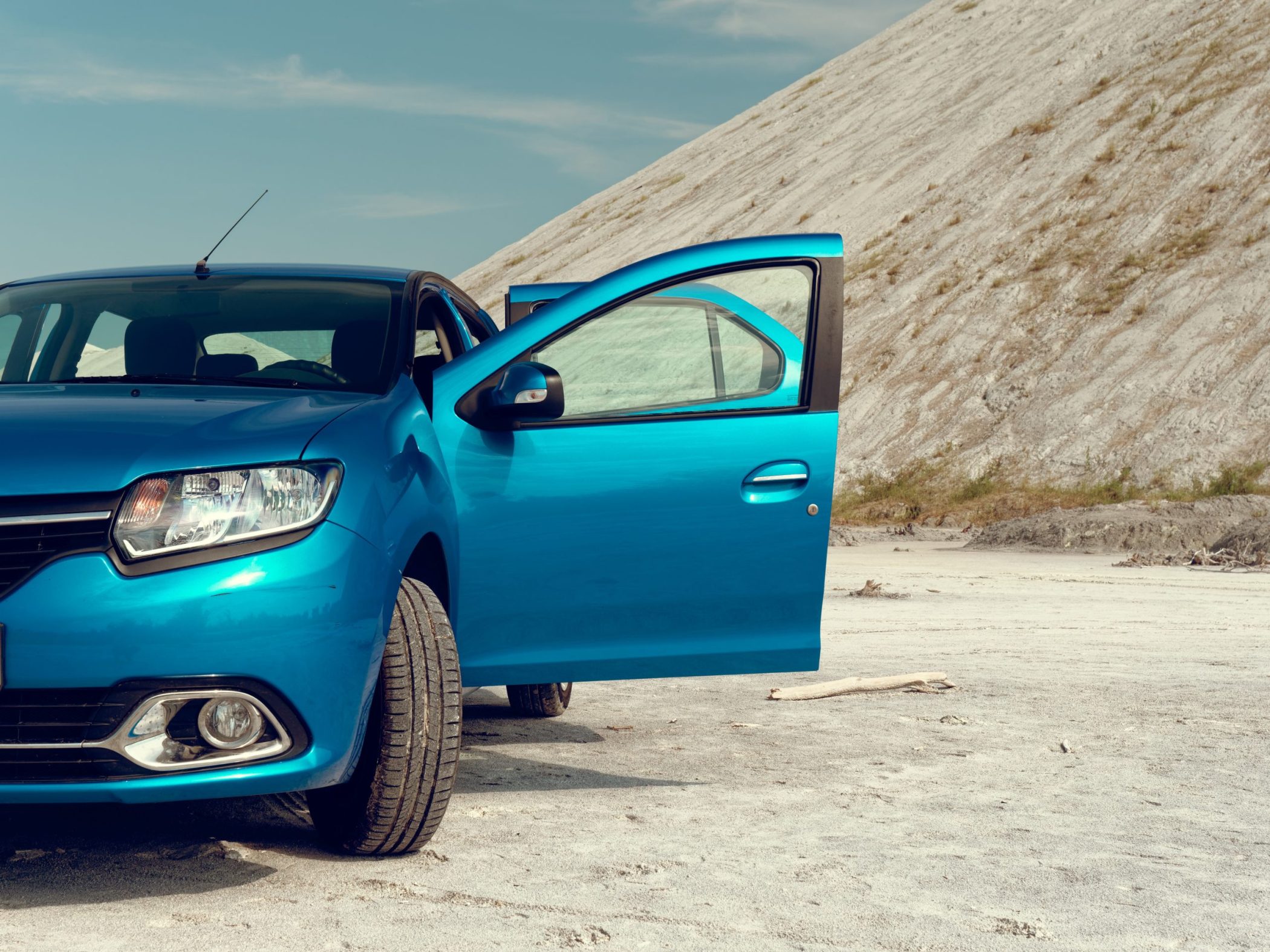 Moderne blauwe auto geparkeerd in een woestijnlandschap.